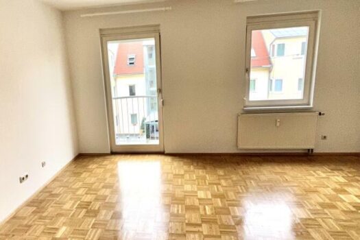 Wohnraum mit offener Küche und Ausgang auf den Balkon